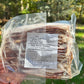 Packaged pork bacon held in front of a natural background with trees.