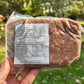 Packaged pork mild sausage held in a hand with a natural background